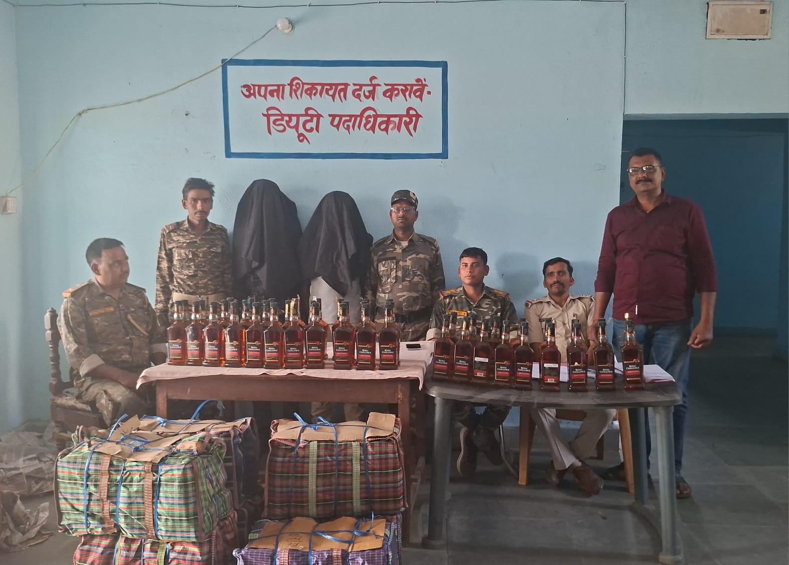 Lesliganj police posing with two arrested liquor smugglers and 266 seized bottles of illegal English liquor.